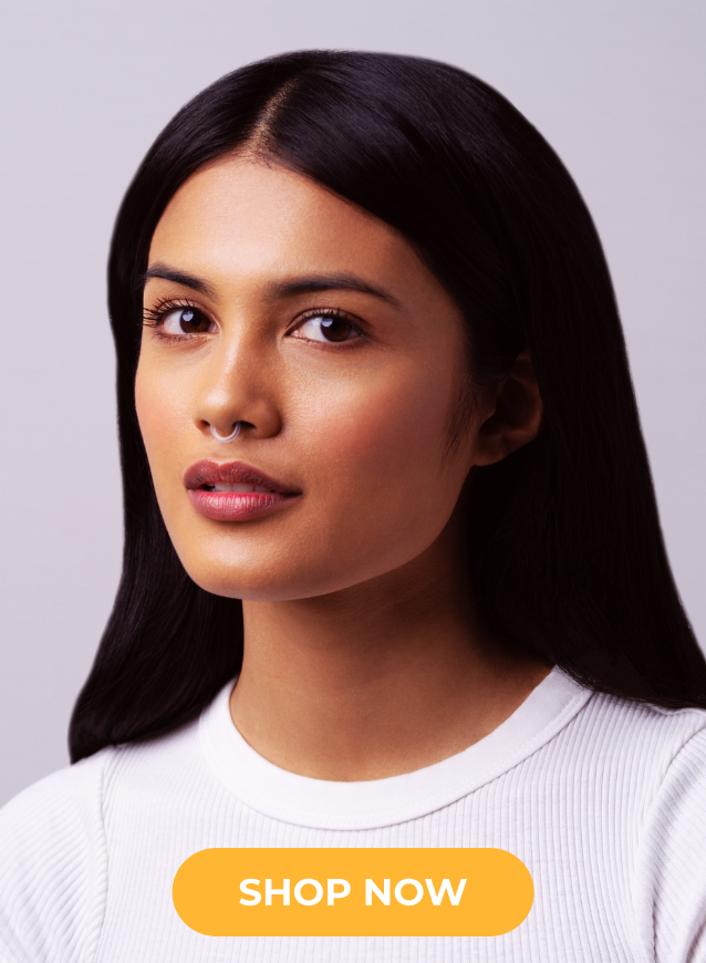 A woman with long, straight black hair wearing a white ribbed crewneck top, shown against a light gray background with an orange 'SHOP NOW' button at the bottom.